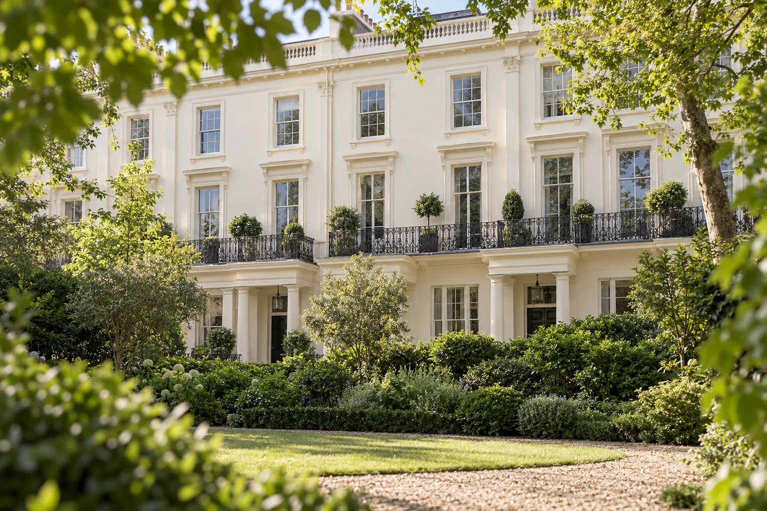 Concept image: stucco garden-square elevation with iron balconies seen through summer foliage